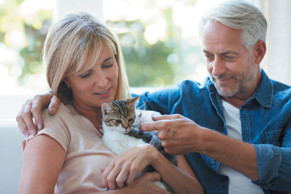 Two older, gray-haired seniors holding a cat.